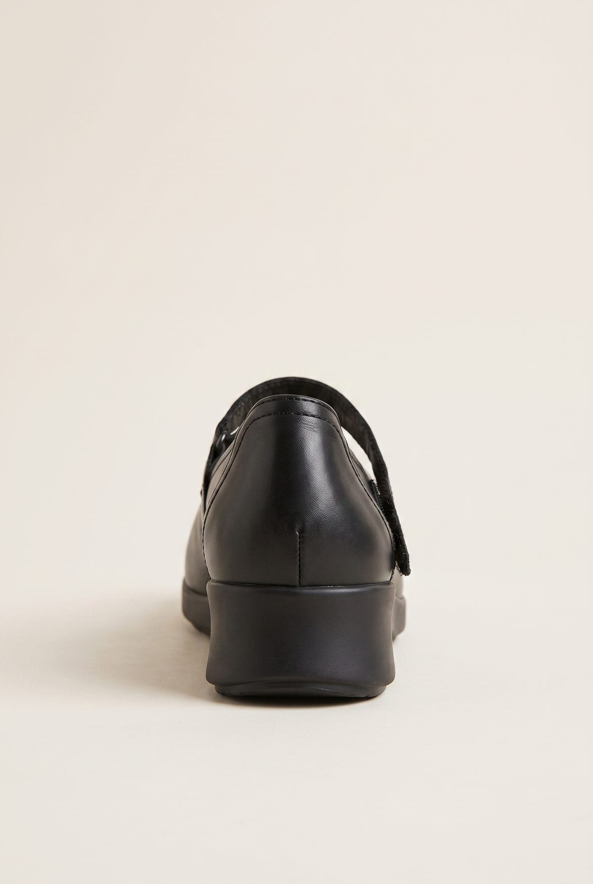 Back view of black leather Mary Jane flat with low platform heel and crossover velcro strap