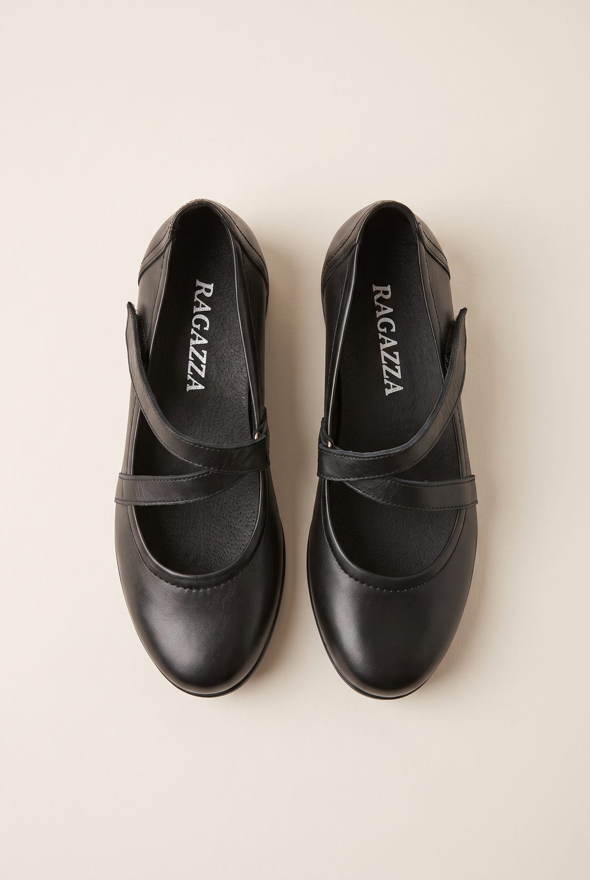 Overhead view of a pair of black leather Mary Jane flats with crossover straps and rounded toes