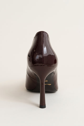 Back view of a dark brown patent stiletto pump showing the glossy heel counter and tall slim heel