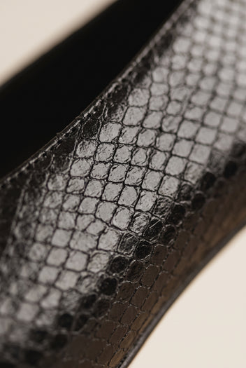 Close-up of black snake-effect leather texture on a pump with a glossy finish and dark edge stitching
