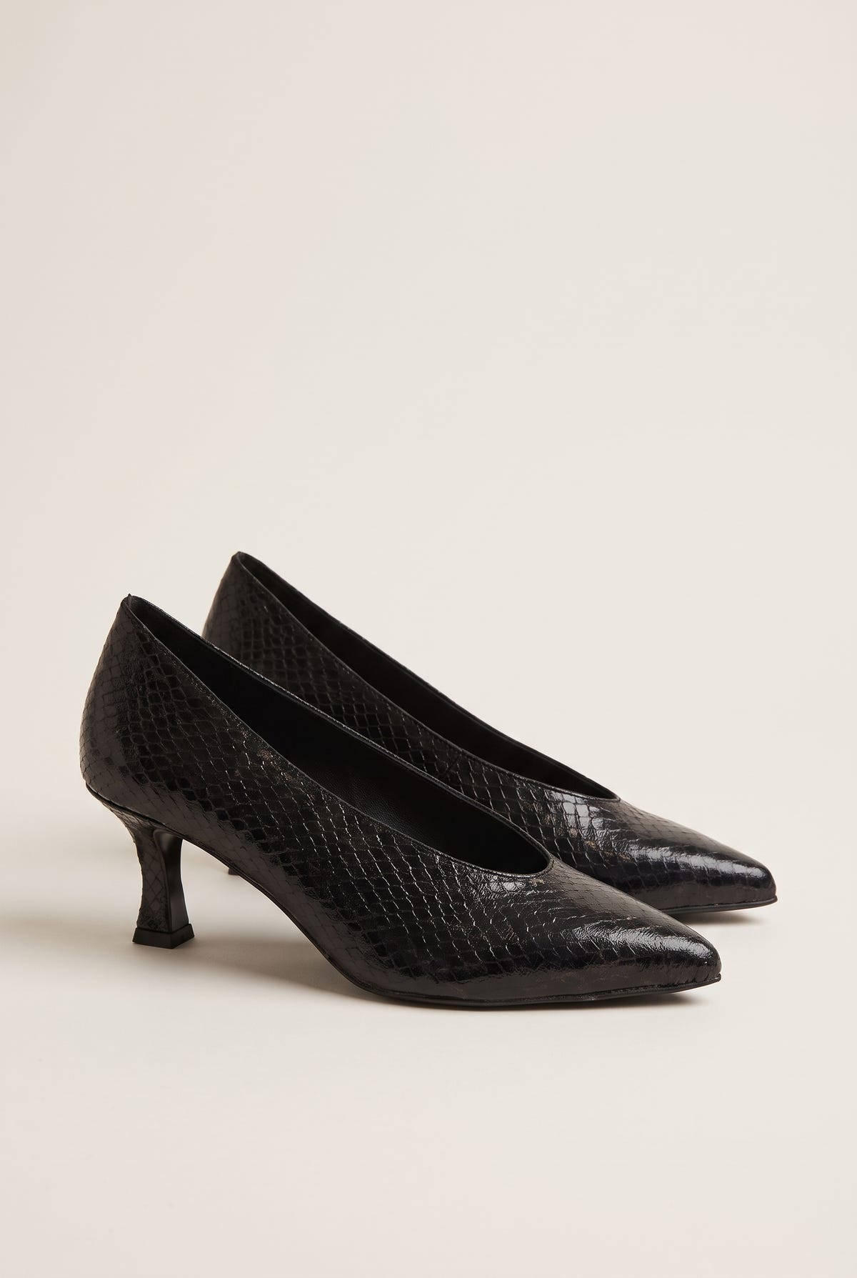 Pair of black snake-effect pointed pumps with kitten heels resting side by side on a light surface