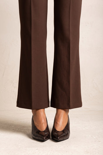 Model wearing brown snake-print kitten heel pumps with brown flared trousers, front view of the feet