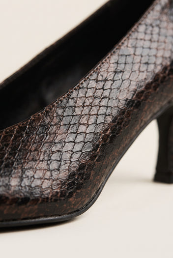 Close-up of brown snake-print leather on a pump with a slim heel and smooth black sole edge