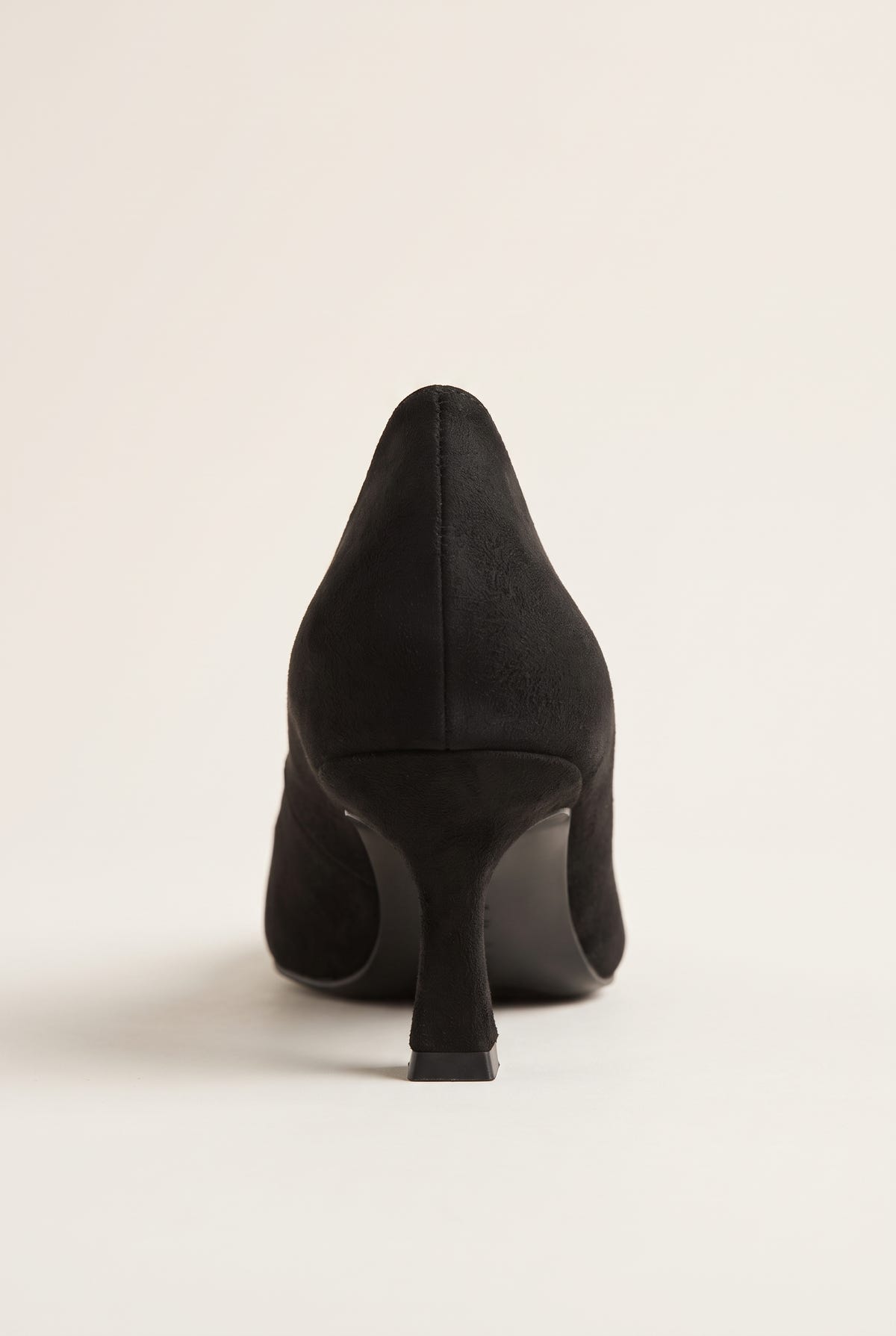 Back view of black suede pump with a smooth heel counter, slim kitten heel and clean rounded sole edge