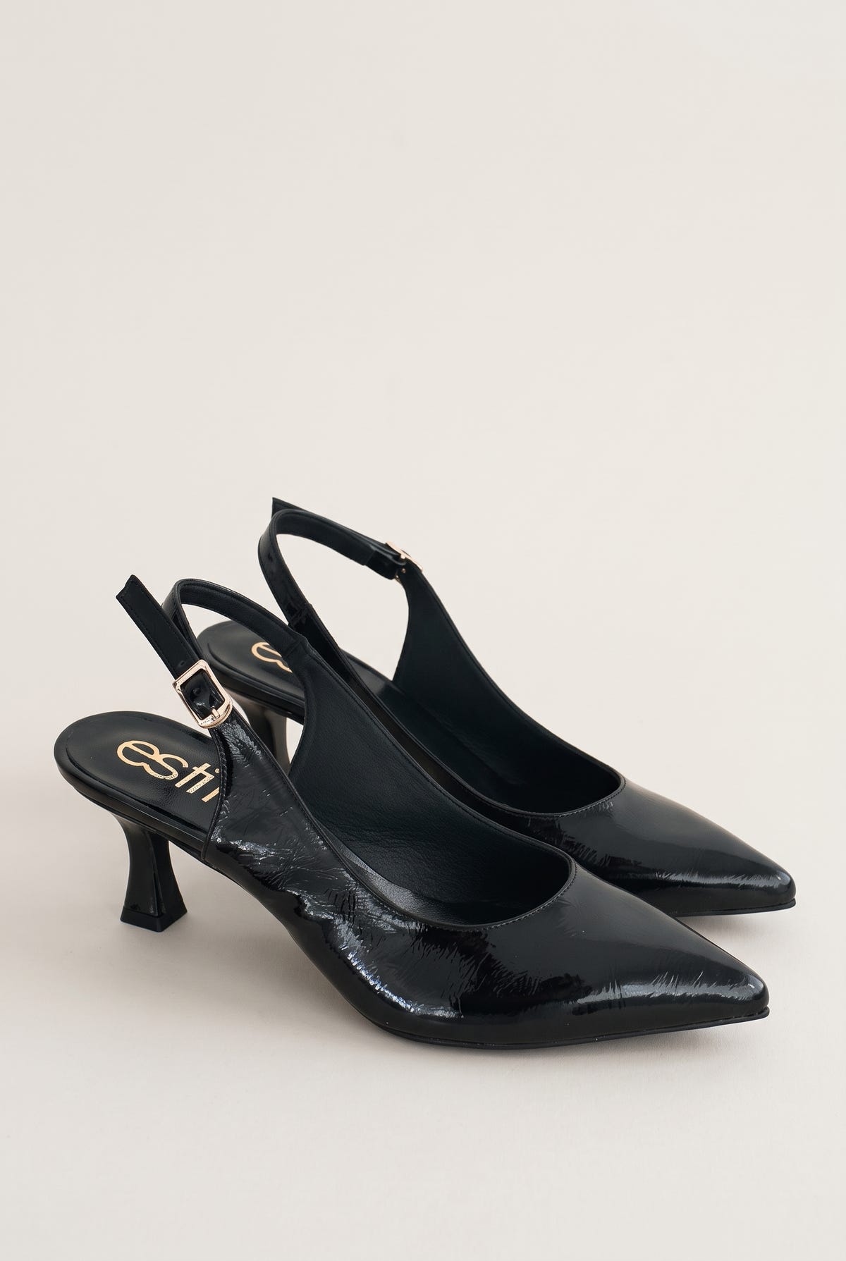 Pair of black patent slingback pumps with pointed toes and buckled ankle straps placed side by side