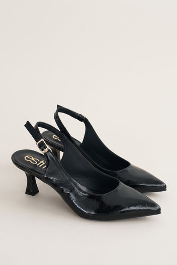 Pair of black patent slingback pumps with pointed toes and buckled ankle straps placed side by side