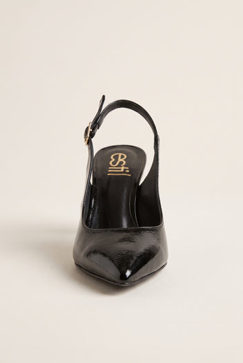 Front view of black patent slingback with pointed toe and buckled strap behind the heel