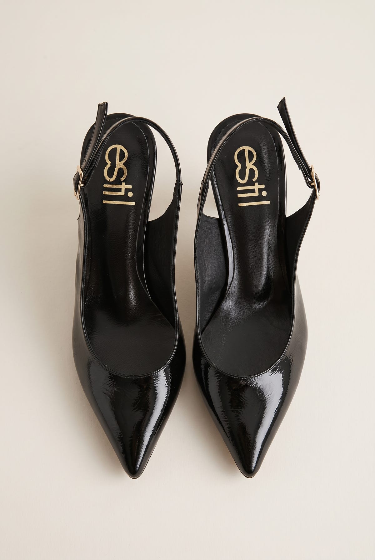 Top view of black patent slingback pumps with glossy buckled straps, pointed toes and black leather insoles