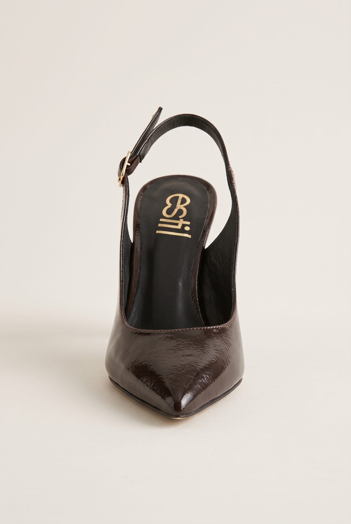 Front view of brown patent slingback with a pointed toe and buckled strap behind the heel