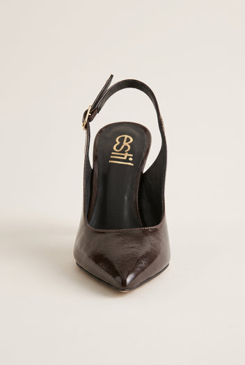 Front view of brown patent slingback with a pointed toe and buckled strap behind the heel