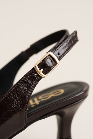 Close-up of brown crinkled patent strap with a gold-tone buckle and a slim kitten heel