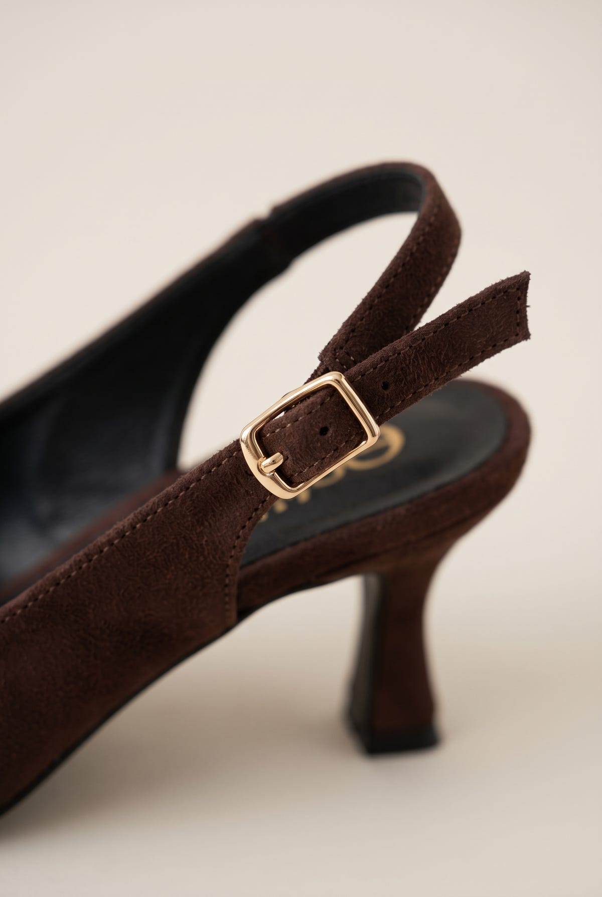 Close-up of brown suede slingback showing the gold-tone buckle on the strap and slim kitten heel