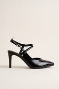 Side view of a black patent pointed toe slingback pump with a crossed ankle strap and slim high heel