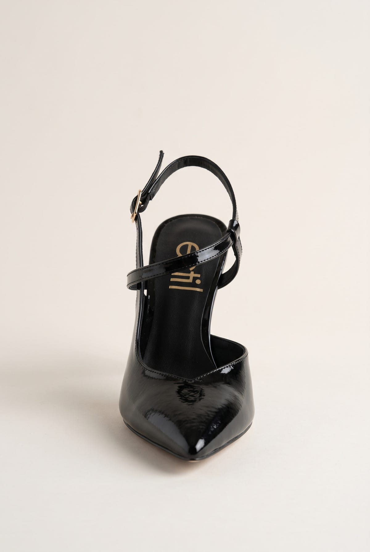 Front view of a black patent slingback pump with pointed toe and ankle strap with a gold buckle
