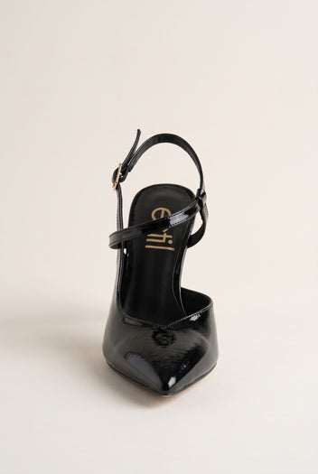 Front view of a black patent slingback pump with pointed toe and ankle strap with a gold buckle