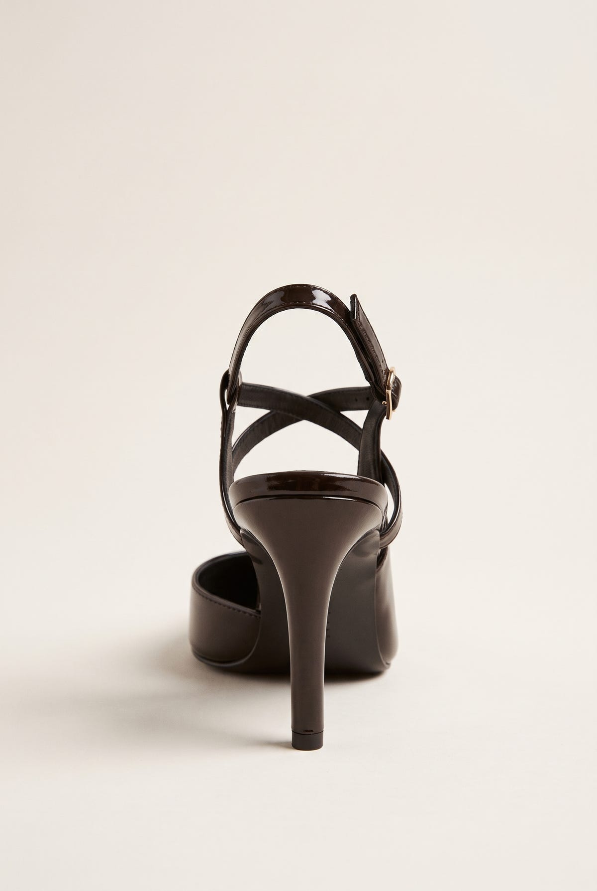 Back view of a brown patent slingback pump with crossed ankle straps and a slim stiletto heel