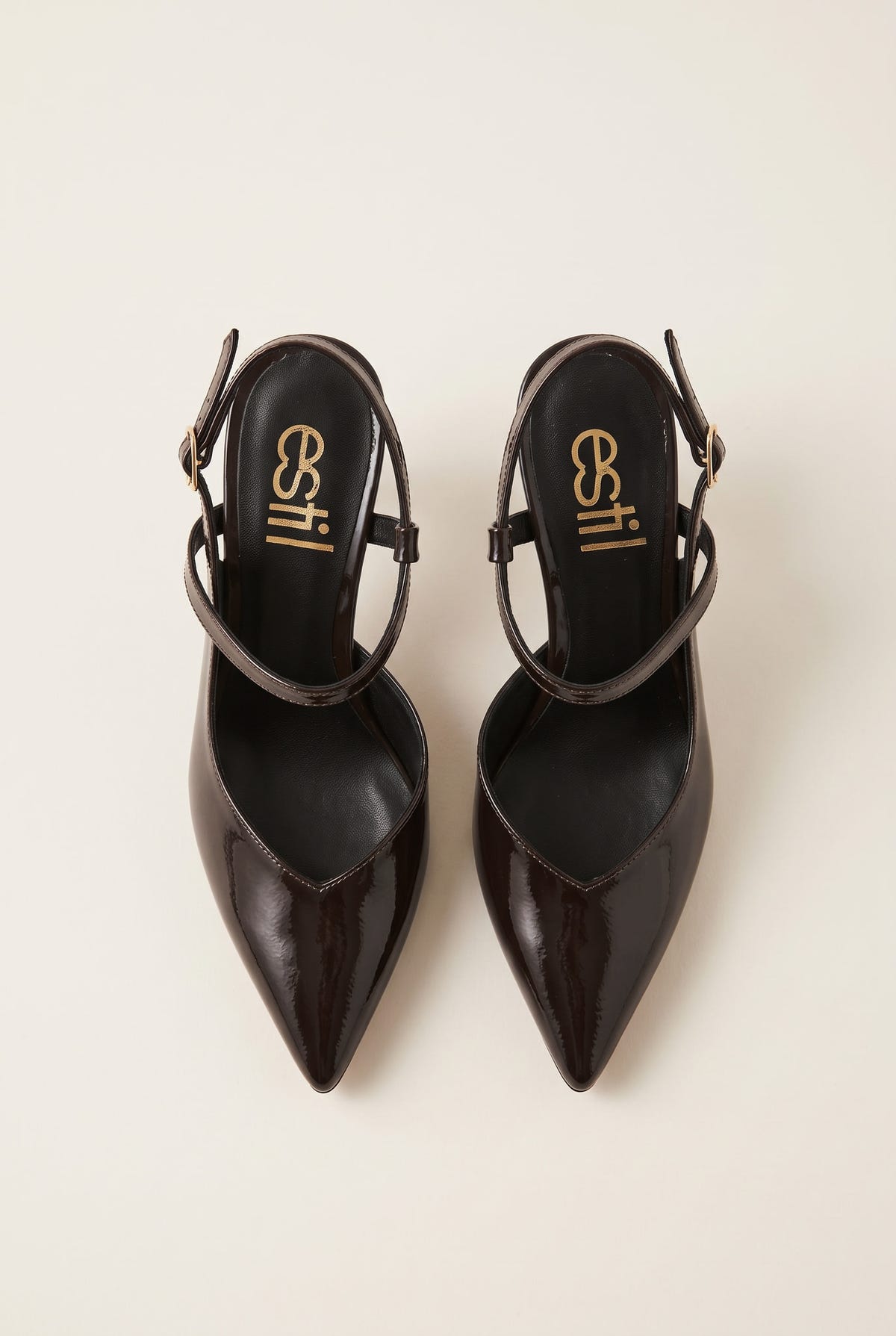Top view of a pair of brown patent slingback pumps with pointed toes and buckled ankle straps