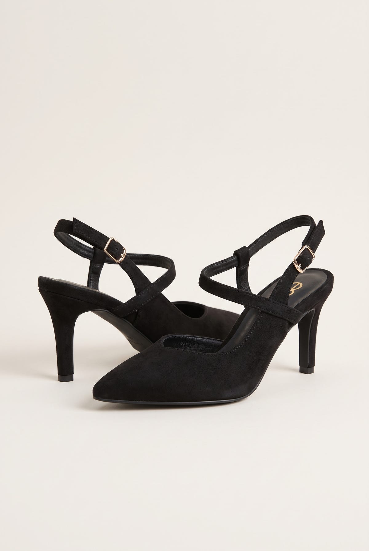 Angled view of black suede slingback pumps showing crossed straps, pointed toes and slim heels