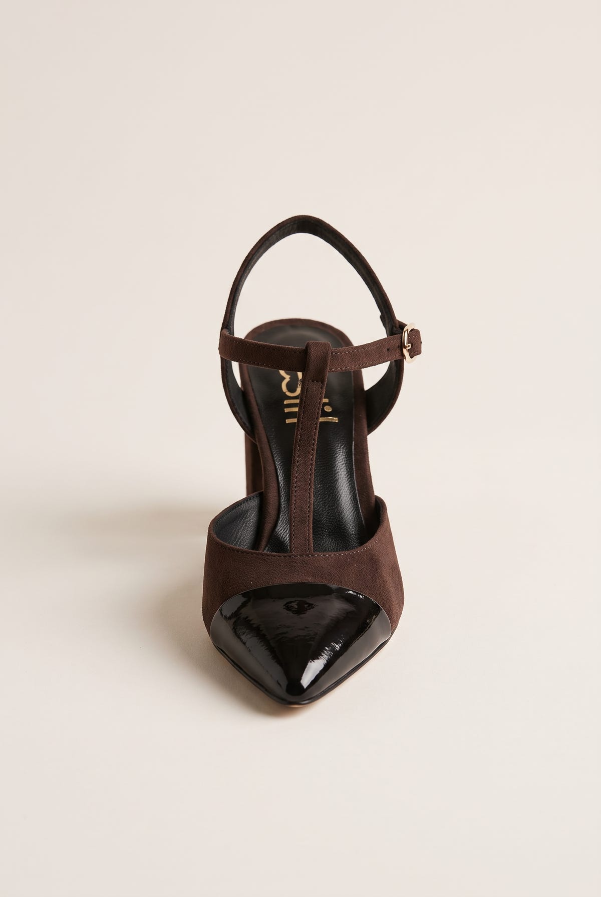 Front view of chocolate suede T-strap pump with black patent pointed toe cap and narrow ankle strap