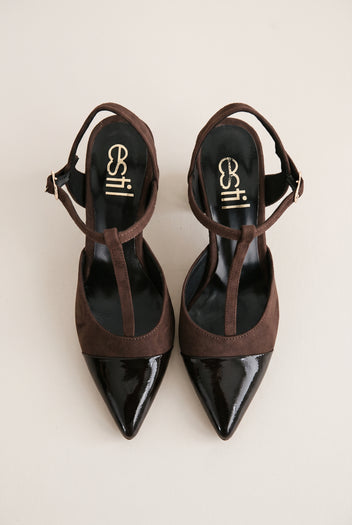 Top view of chocolate suede T-strap pumps with black patent pointed toes placed side by side