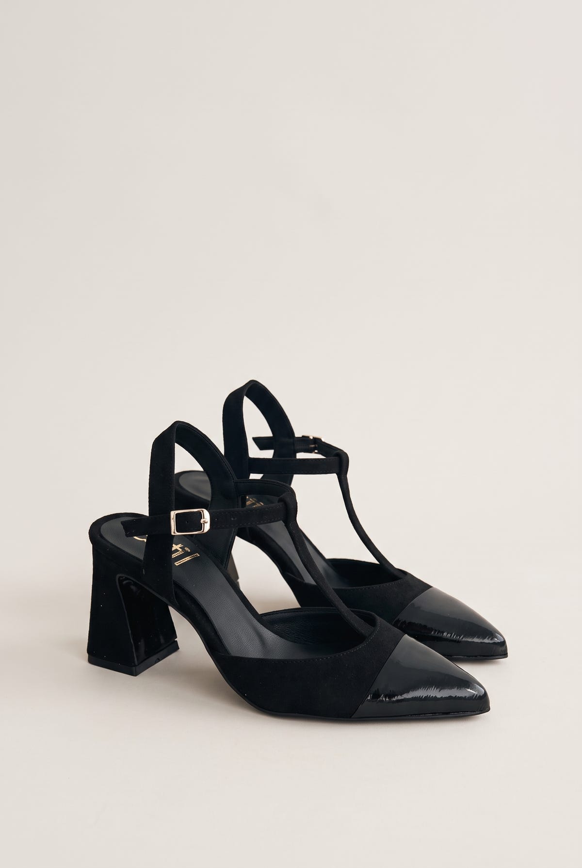 Pair of black suede T-strap pumps with patent toe caps in angled view showing flared block heels