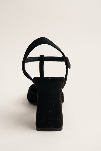 Rear view of black suede T-strap pump showing arched ankle strap and flared block heel
