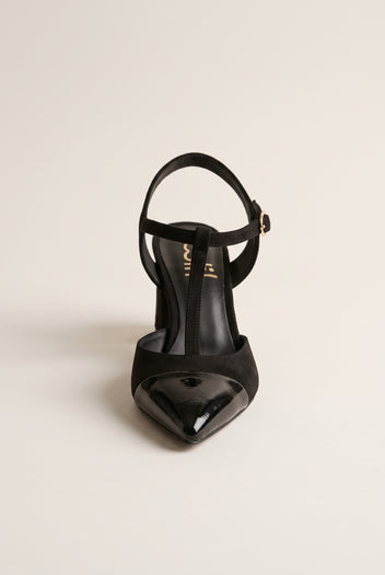Front view of black suede T-strap pump showing patent toe cap and buckle on ankle strap