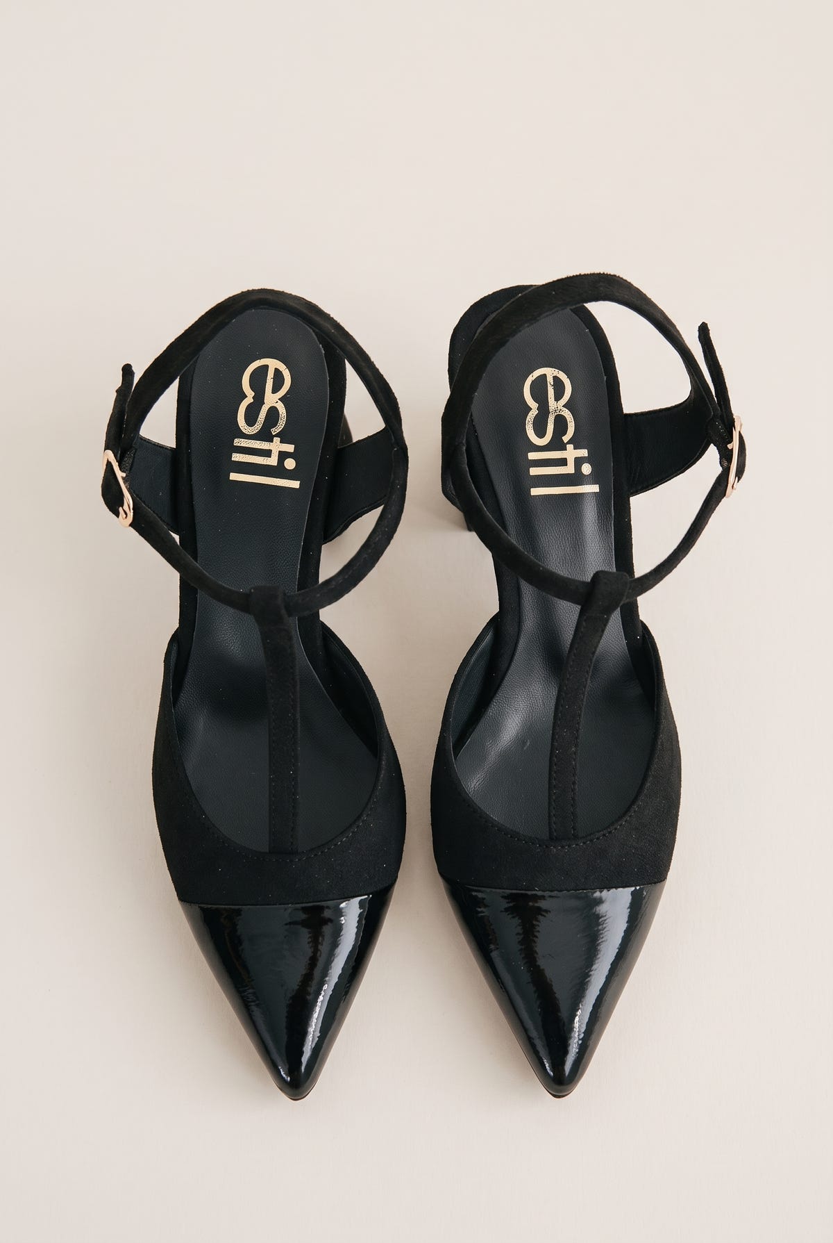 Top view of black T-strap pumps with suede body, patent pointed toe caps and ankle buckles