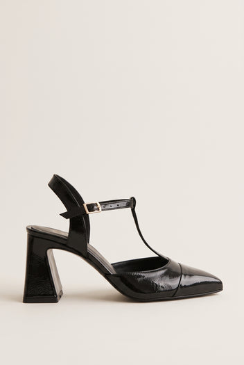 Black patent T-strap pump with pointed toe, ankle strap buckle and flared block heel in side view