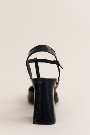 Black patent T-strap pump in rear view showing ankle strap, flared block heel and back counter