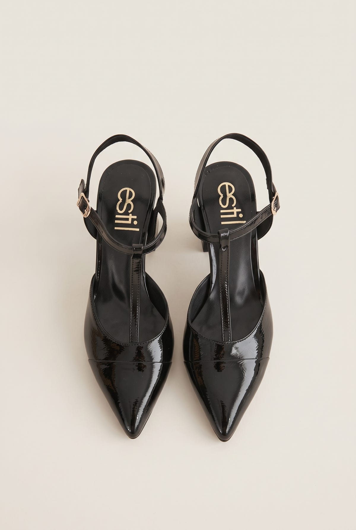 Pair of black patent T-strap pumps viewed from the back showing ankle straps and pointed toes