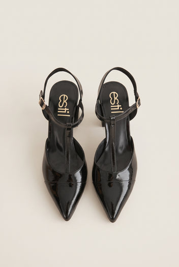 Pair of black patent T-strap pumps viewed from the back showing ankle straps and pointed toes