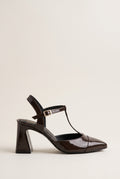 Brown patent T-strap pump with pointed toe, ankle strap buckle and flared block heel in side view