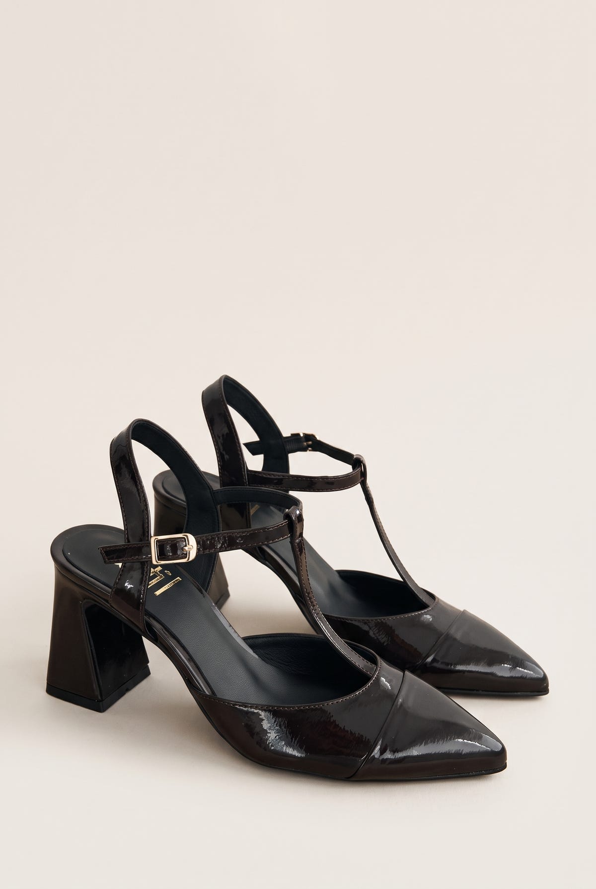 Pair of brown patent T-strap pumps in angled view showing ankle straps and flared block heels
