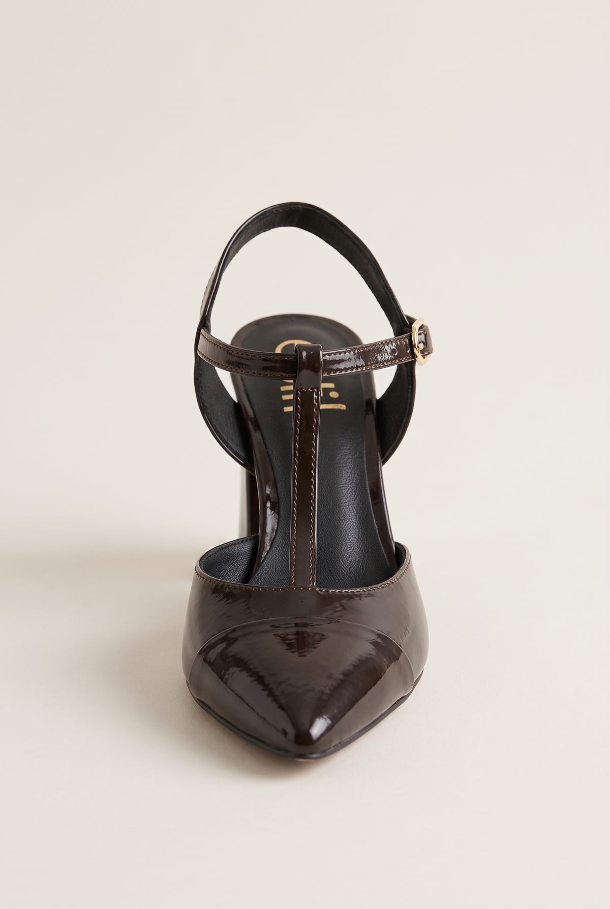 Brown patent T-strap pump in front view showing pointed toe cap and thin ankle strap over instep
