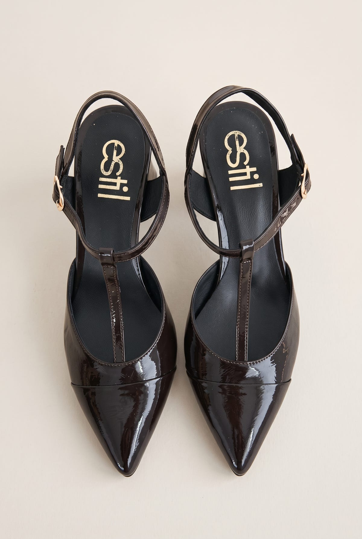 Pair of brown patent T-strap pumps in top view showing pointed toes and ankle straps