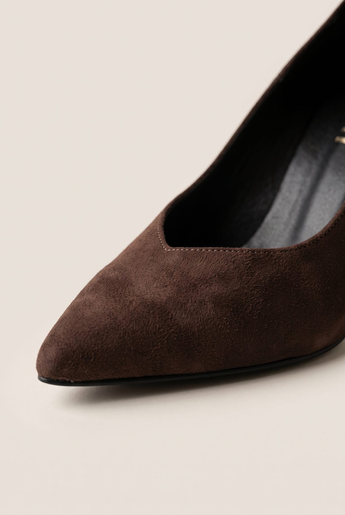 Close-up of brown suede pump vamp showing pointed toe edge, low cut and smooth suede texture