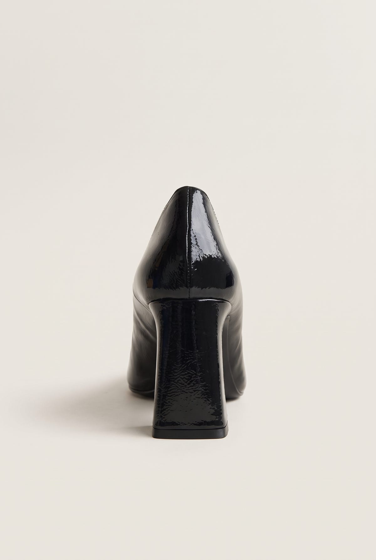 Black patent pointed-toe pump in front view showing narrow toe and tall flared block heel