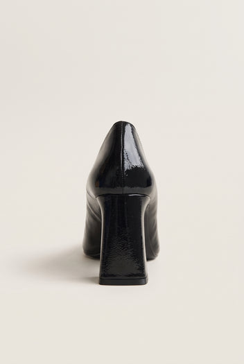 Black patent pointed-toe pump in front view showing narrow toe and tall flared block heel