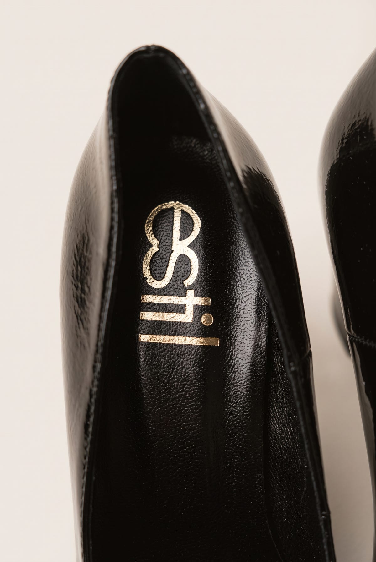 Close-up of black patent pump interior showing padded black insole and smooth lining at the heel opening