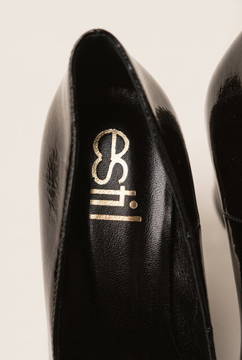 Close-up of black patent pump interior showing padded black insole and smooth lining at the heel opening