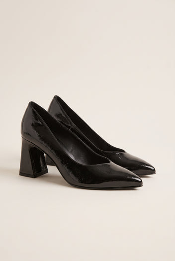 Pair of black patent pointed-toe pumps in three-quarter view showing flared block heels and glossy finish