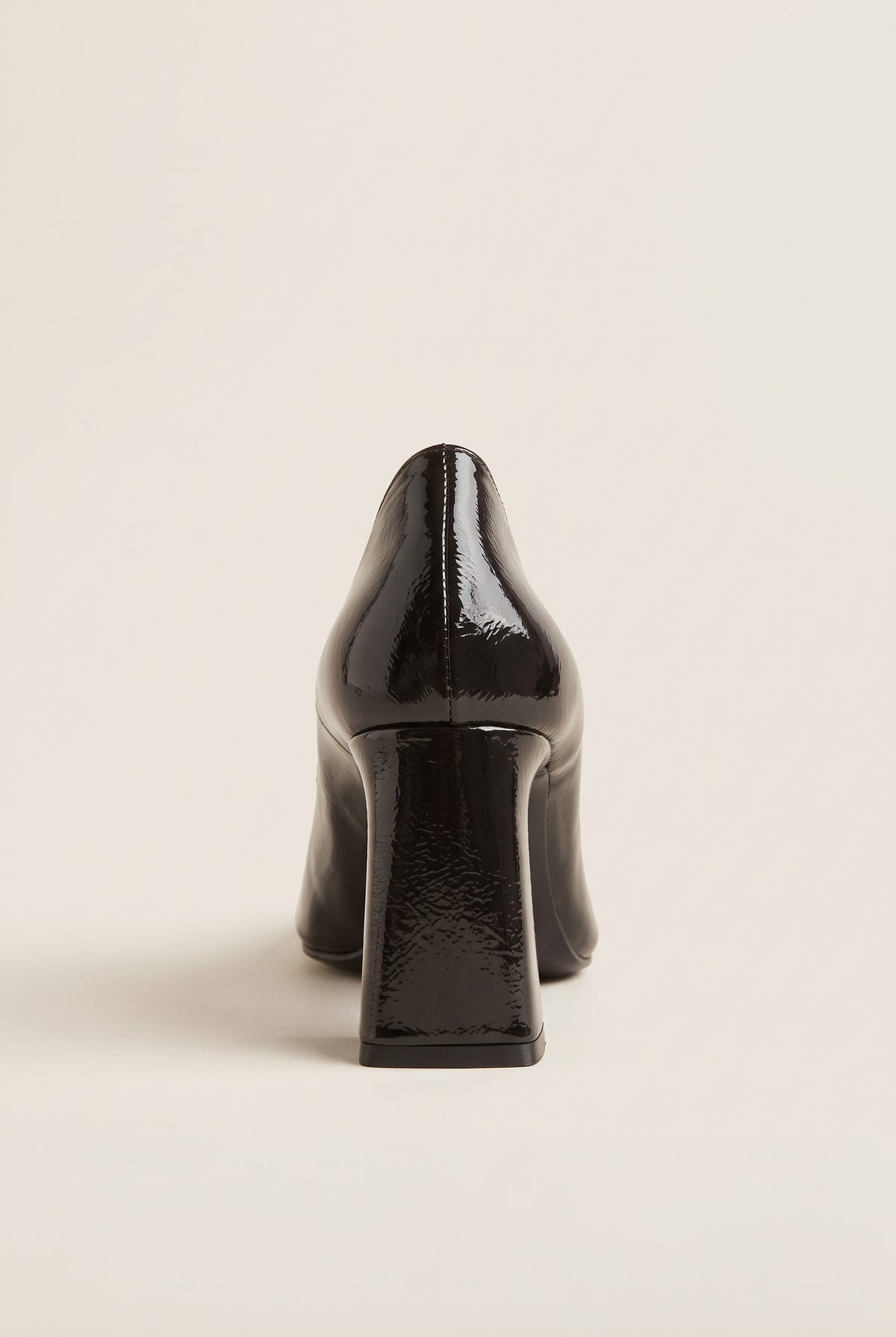 Rear view of brown patent pointed-toe pump showing narrow block heel and glossy back counter
