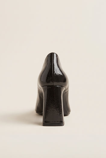 Rear view of brown patent pointed-toe pump showing narrow block heel and glossy back counter