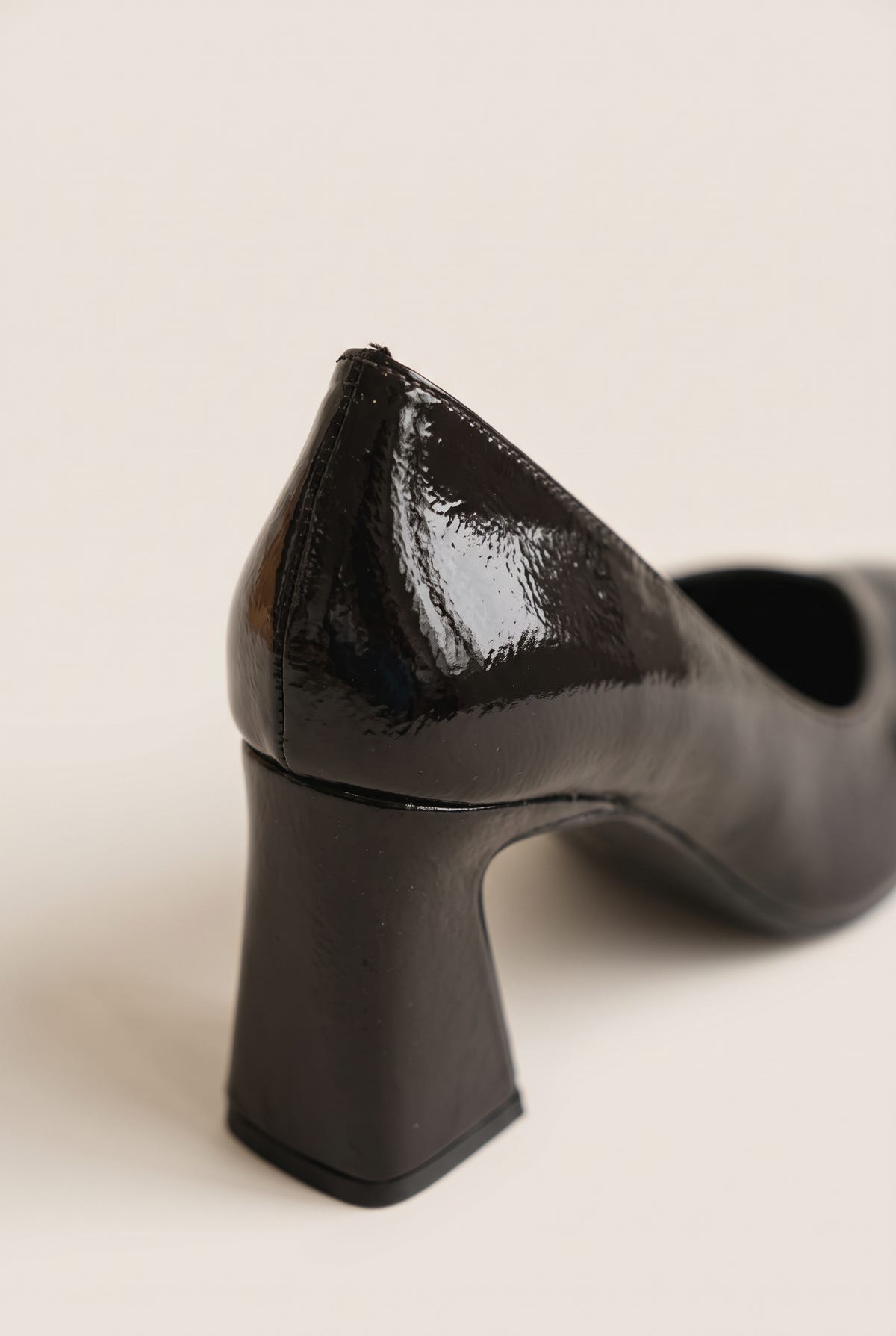 Close-up of brown patent pump showing glossy toe, low cut edge and flared block heel base