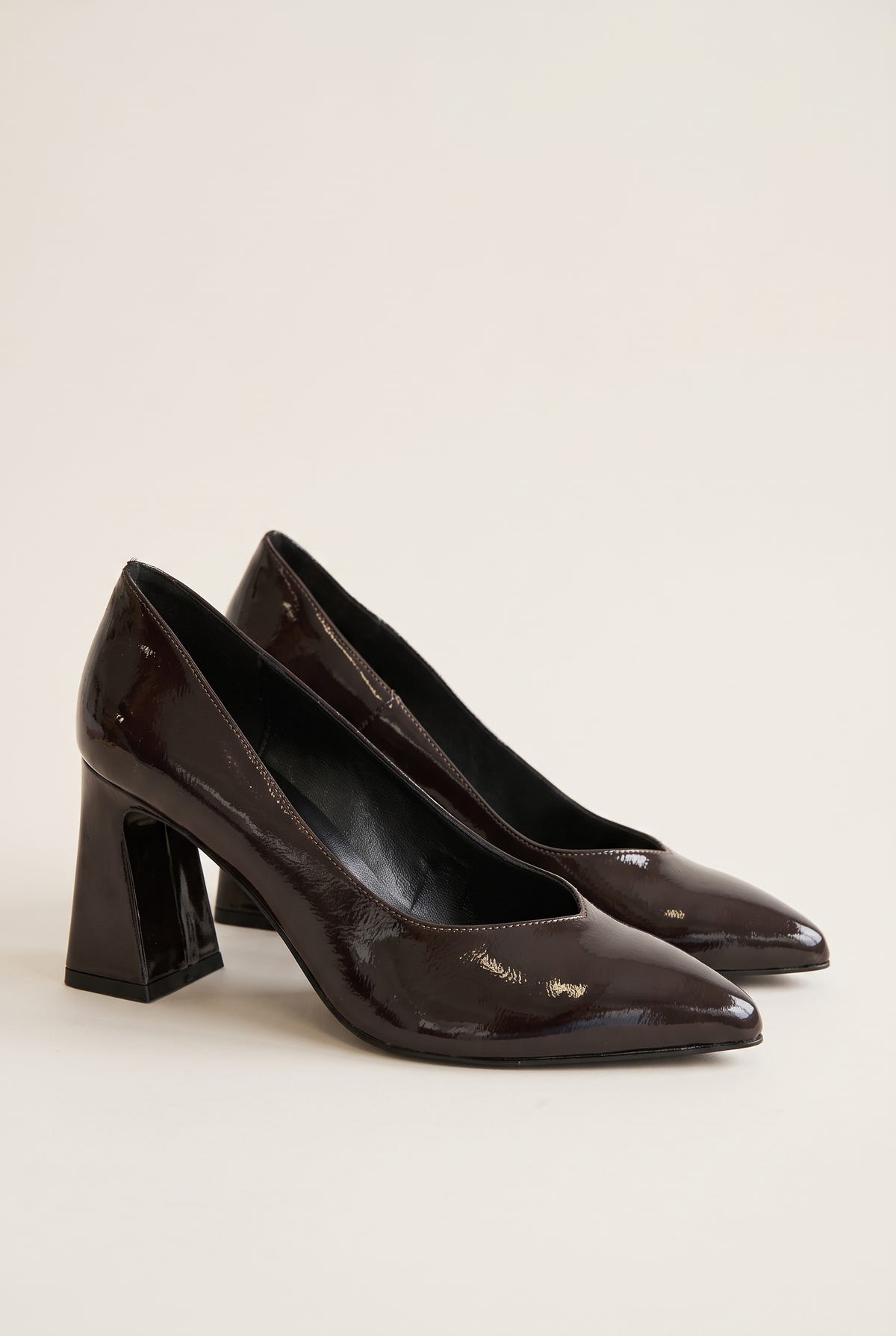Pair of brown patent pointed-toe pumps in angled view showing glossy shine and flared block heels