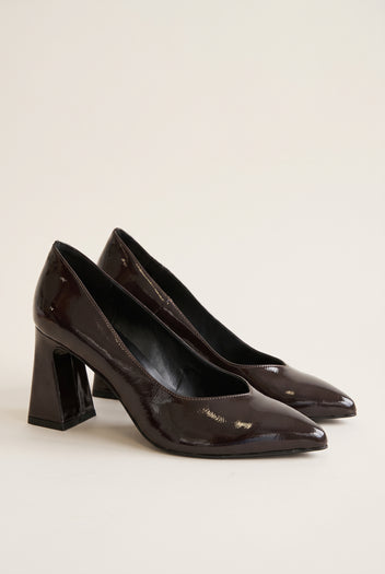 Pair of brown patent pointed-toe pumps in angled view showing glossy shine and flared block heels