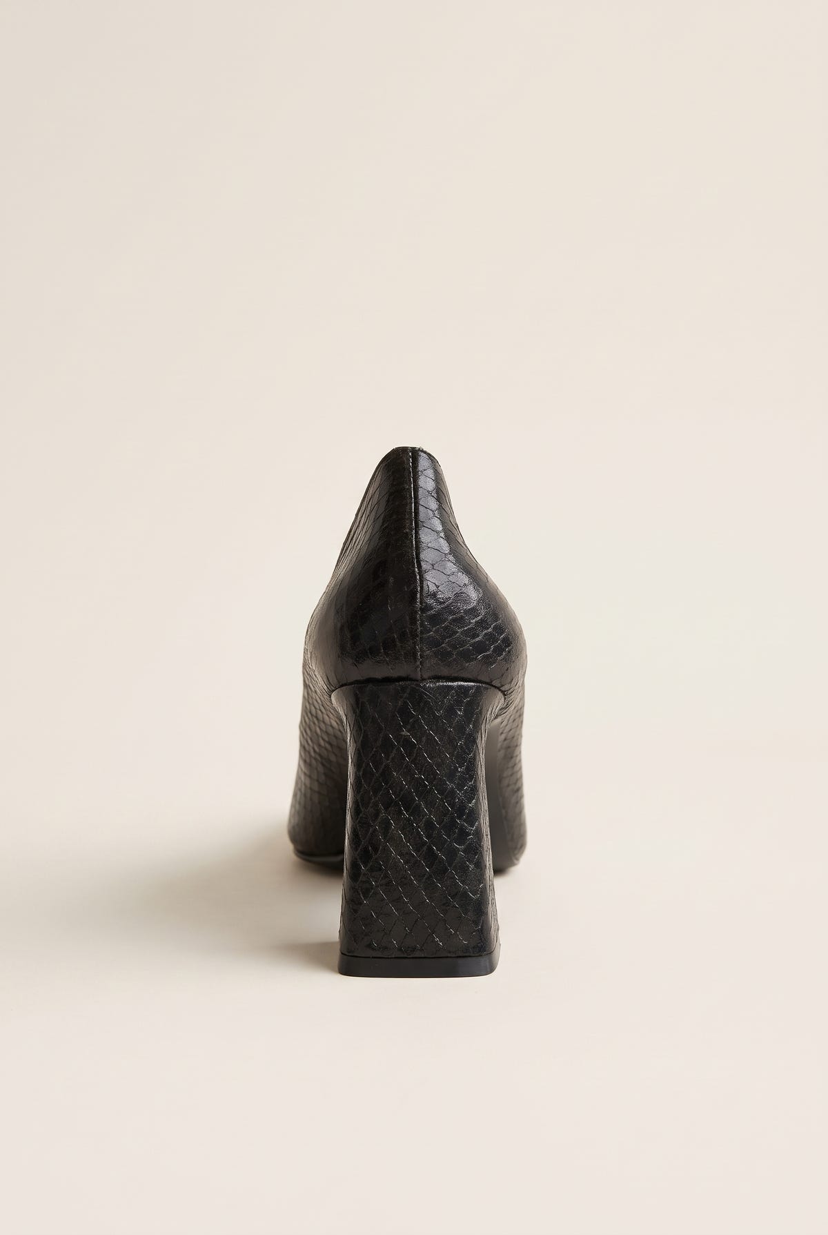 Black snake-embossed pump in rear view showing flared block heel and textured back counter