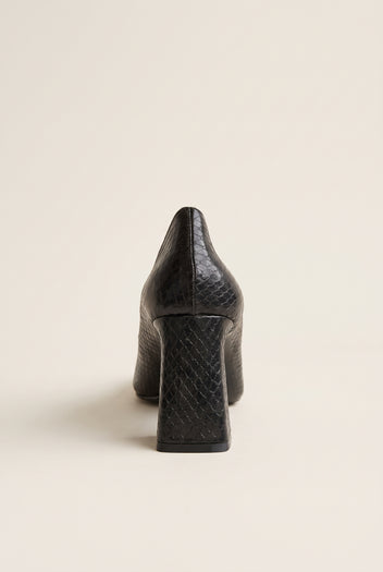 Black snake-embossed pump in rear view showing flared block heel and textured back counter