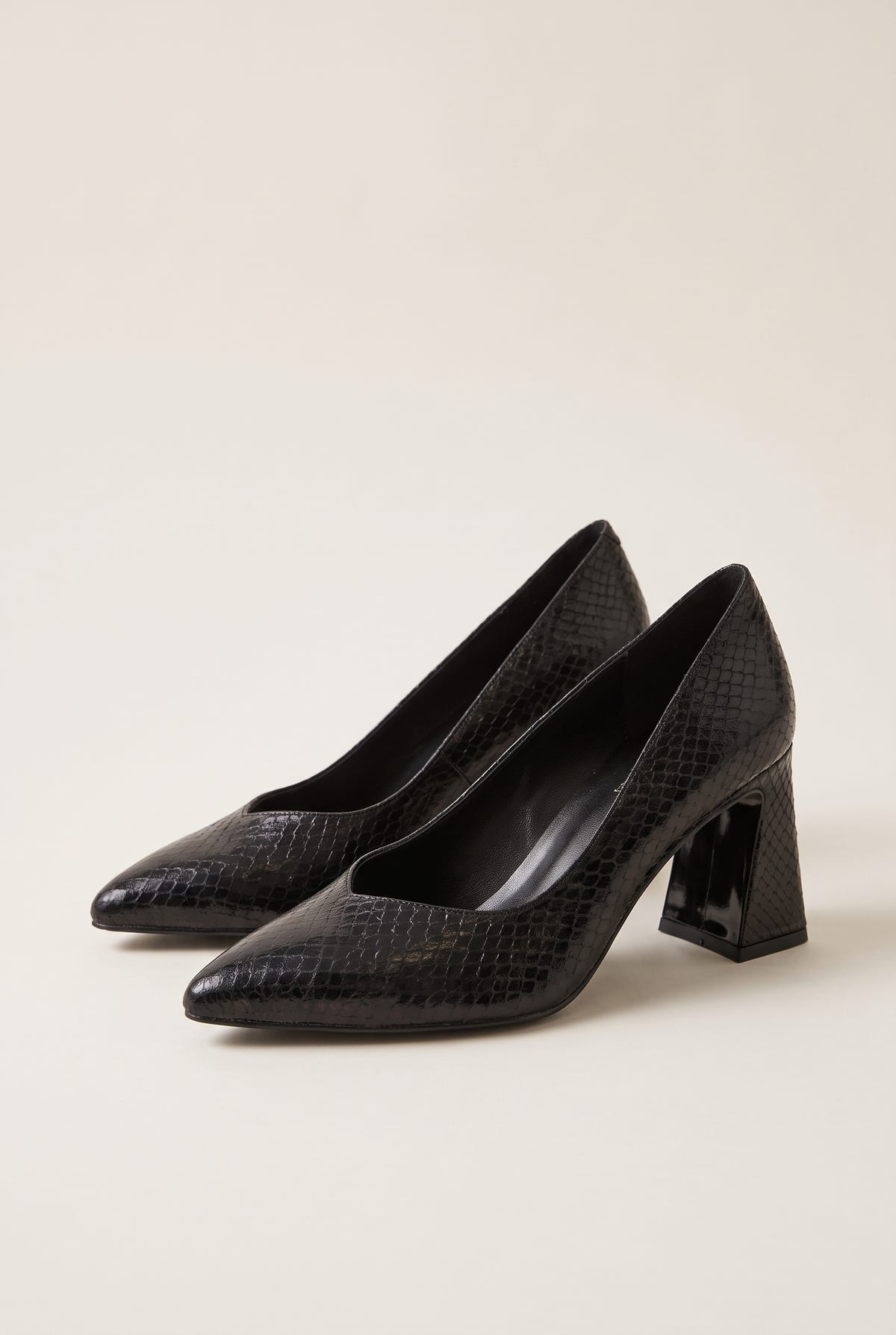 Pair of black snake-embossed pumps in angled view showing pointed toes and flared block heels